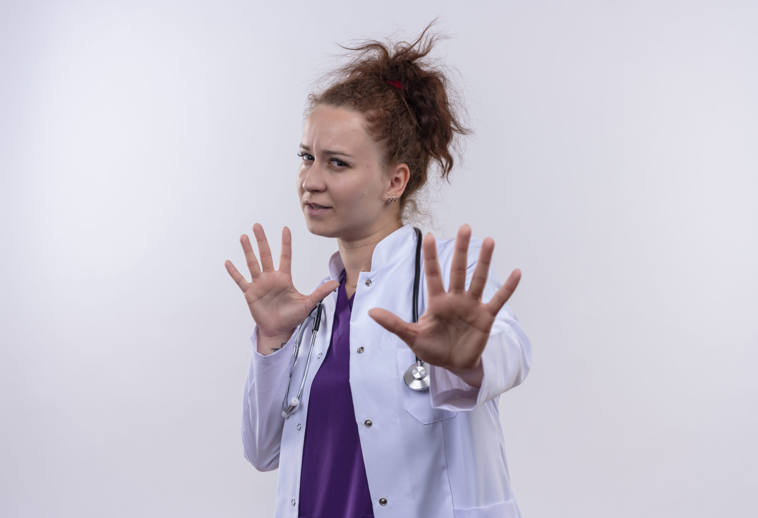 young woman doctor wearing white coat with stethoscope worried making stop sign with hands standing over white background